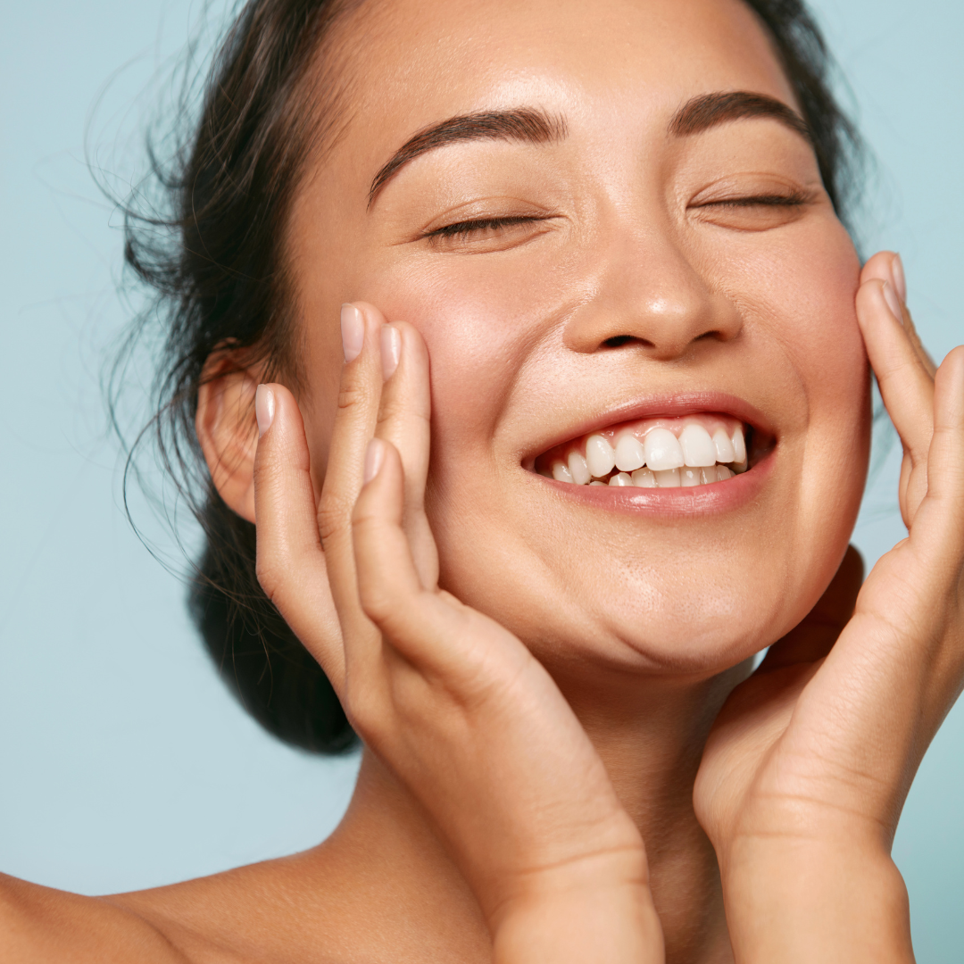 smiling woman touching her hydrated, radiant, glowing skin